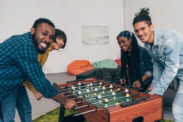 smiling group of multicultural friends playing table football