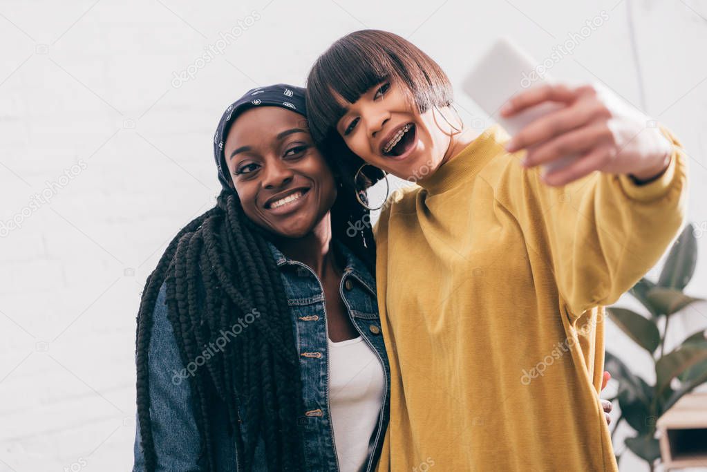 smiling young multicultural female friends taking selfie 