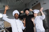 Lächelnde multikulturelle Köche amüsieren sich in der Restaurantküche