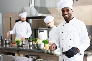 African american chef cooking by his multiracial colleagues clipart