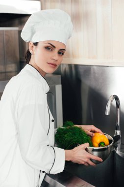 Genç kadın aşçı mutfakta sebze yıkama