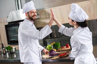 Mutfak tezgahı tarafından yüksek beş veren aşçıların profesyonel ekibi