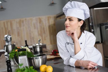 attractive pensive chef looking away at restaurant kitchen