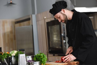 yakışıklı Şef kesme biber Restoran mutfak at yan görünüm
