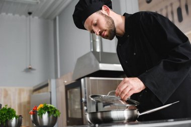yakışıklı Şef ile kızartma tavası, lokanta mutfağı pişirme yan görünüm
