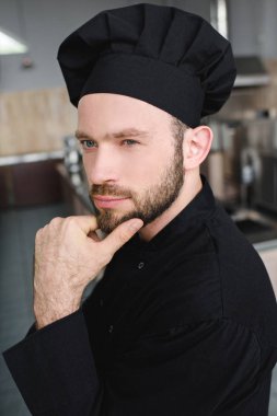 pensive handsome chef looking away at restaurant kitchen clipart