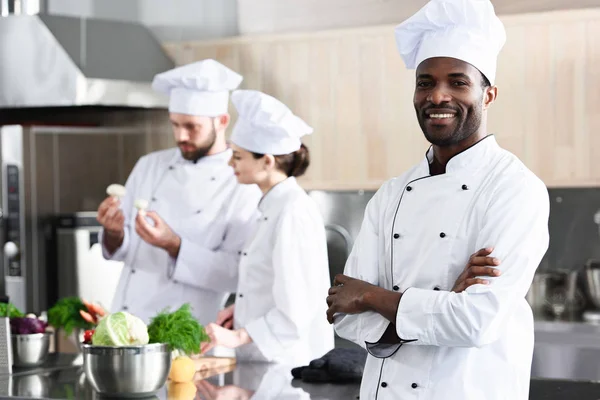 African American Chef Stojąc Założonymi Rękami Przed Kolegami Kuchnię — Zdjęcie stockowe