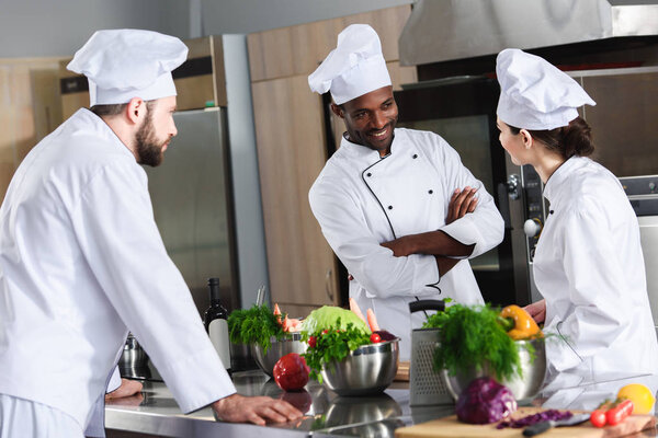 Multiracial chefs team discussing new recipe by kitchen counter