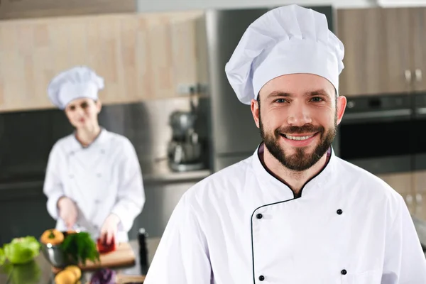 Glimlachend Mannelijke Chef Kok Voor Zijn Vrouwelijke Collega Keuken — Stockfoto