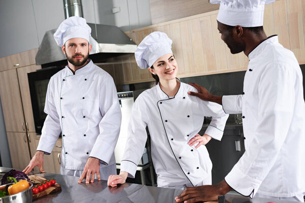 Multiracial team of cooks working by kitchen counter