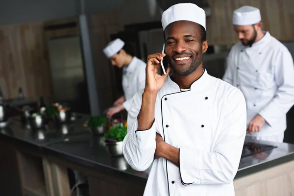 微笑的非洲裔美国人厨师在餐馆厨房讲智能手机 — 图库照片