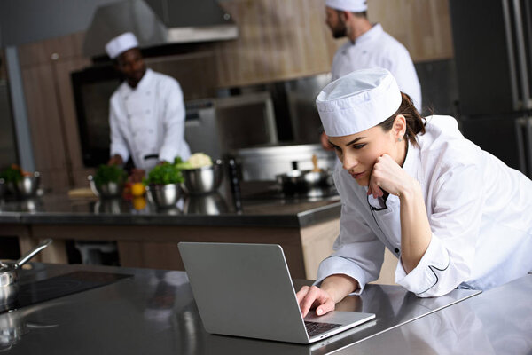 attractive chef using laptop at restaurant kitchen