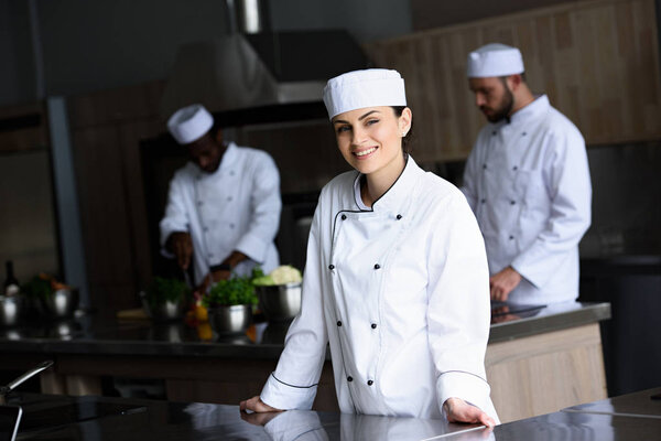 smiling attractive chef looking at camera at restaurant kitchen