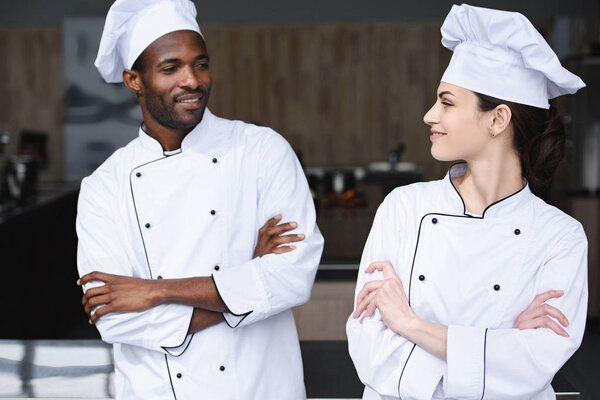 multicultural chefs looking at each other at restaurant kitchen