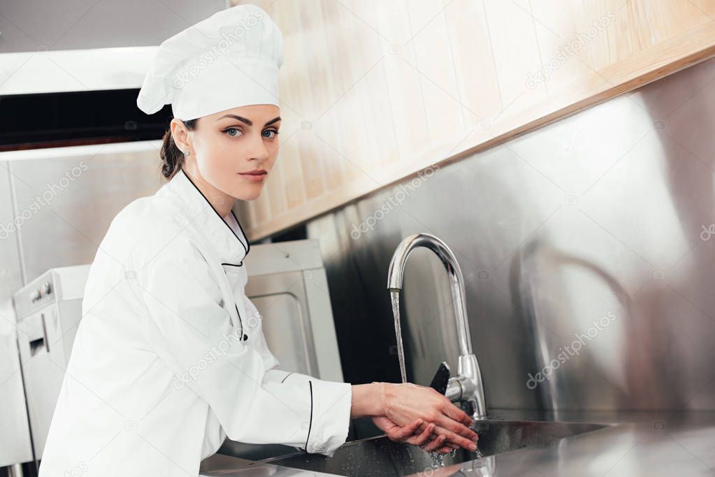 Female chef washing hands over kitchen sink