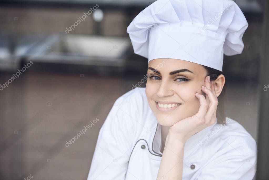 smiling attractive chef looking at camera at restaurant kitchen