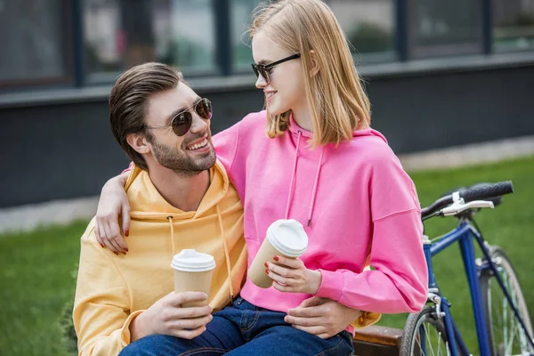 Sonriente Elegante Pareja Gafas Sol Sentado Banco Con Papeles Tazas —  Fotos de Stock