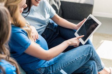 Arkadaş ve hamile kadın evde tablet kullanarak kırpılmış görüntü