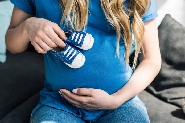 Przycięte Zdjęcie Kobiety Ciąży Dotykając Brzuch Buty Dziecięce — Zdjęcie stockowe
