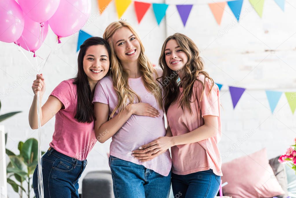 smiling multicultural women touching pregnant friend belly at baby-party