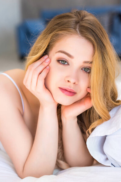 портрет привлекательной мечтательной девушки, лежащей в постели
