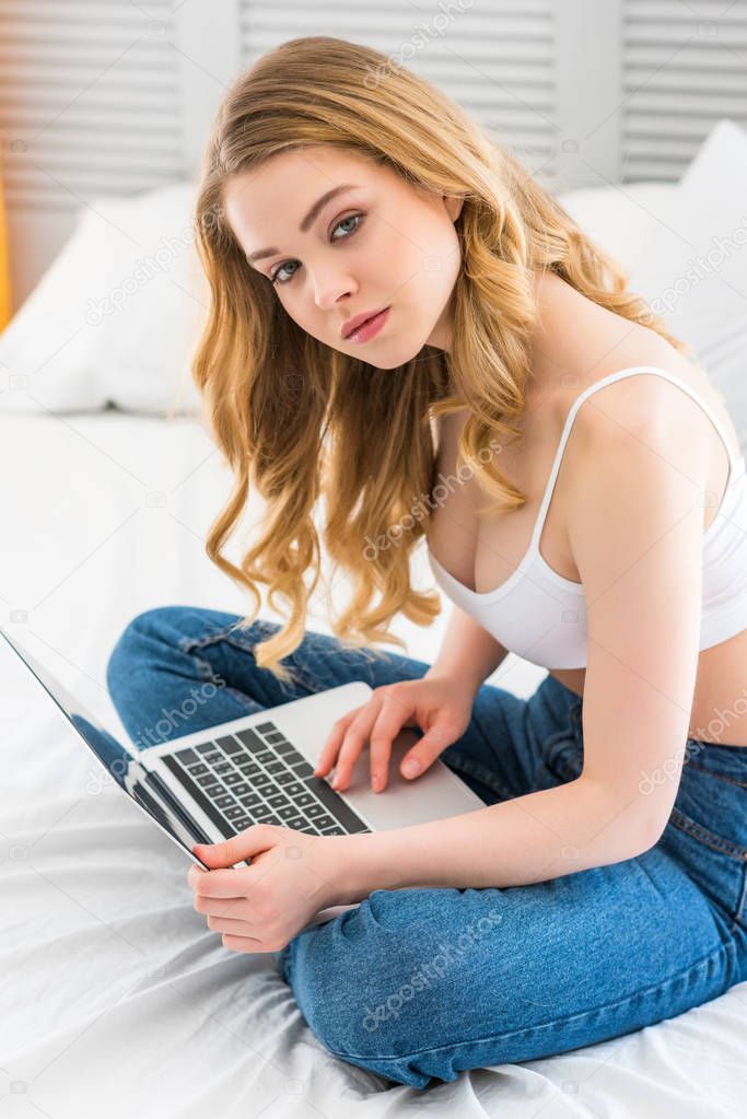 attractive young woman using laptop in bedroom