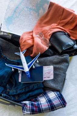 Giysi, pasaport, hava bilet, harita ve uçak modeli ile seyahat çantası