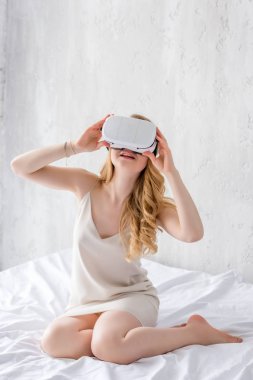 sarışın kadın yatak odasında VR kulaklık kullanarak
