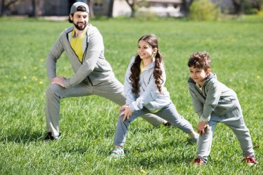 Baba ile kızı ve oğlu Parkı otsu çayır üzerinde fiziksel egzersiz yaparak