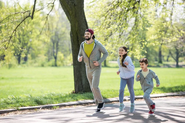 happy sportive family running on path in park