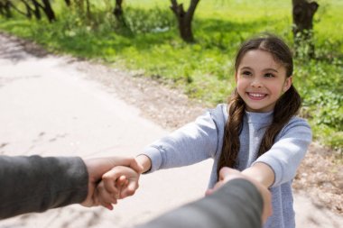 cropped image of man holding smiling daughter hands in park clipart