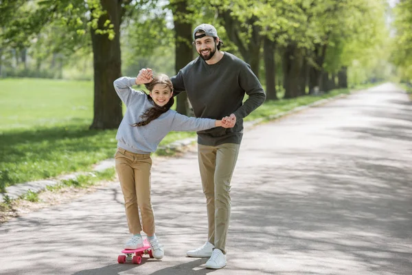 笑顔の父娘公園でスケート ボードに乗ることを支援 — ストック写真