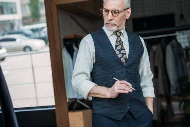 üst düzey terzi Dikiş Atölyesi'nde kalem tutan ve aşağı bakıyor