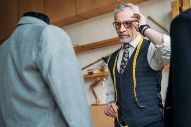 gözlük dokunmaktan ve ceketler Dikiş Atölyesi'nde mankenler üzerinde seyir yakışıklı terzi