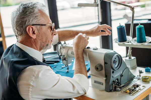 вид сбоку на иголку швейной машинки старшего портного в швейной мастерской
