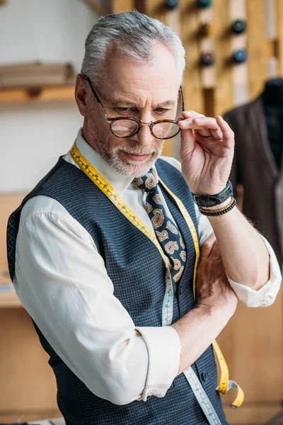 Guapo Sastre Tocando Gafas Mirando Hacia Abajo Taller Costura — Foto de Stock