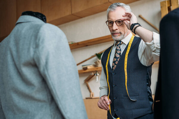 Handsome Tailor Touching Glasses Looking Jackets Mannequins Sewing Workshop — Stock Photo, Image