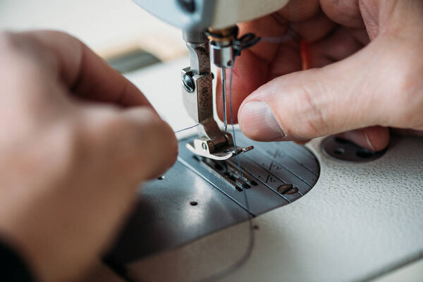 cropped shot of tailor working with sewing machine