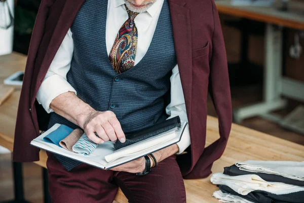 Schnappschuss Des Schneiders Mit Katalog Der Stofftypen Auf Dem Tisch — Stockfoto