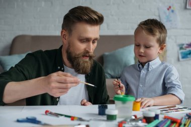 Baba ve boyalar ve fırçalar çizim resimleri birlikte evde şirin küçük oğul portresi