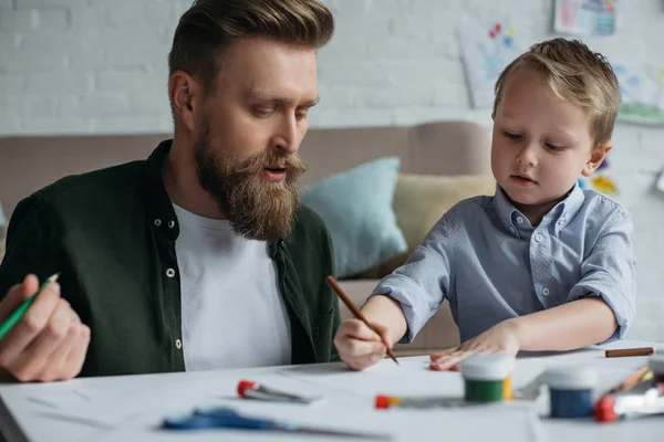 父亲和可爱的小儿子与五颜六色的铅笔一起画在家里的图片 — 图库照片