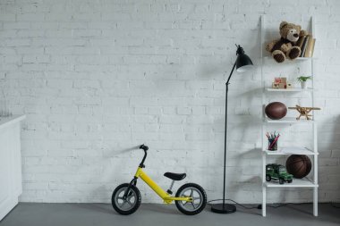 close up view of empty childish room with balance bike against white brick wall clipart