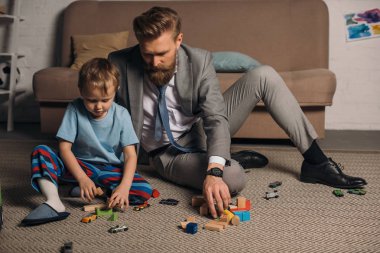 businessman in suit and little son playing with wooden blocks on floor at home, work and life balance concept clipart