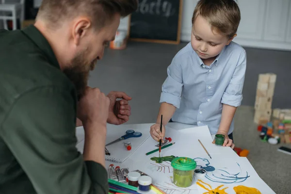 Маленький Хлопчик Пензлем Фарбами Малює Фотографію Разом Батьком Вдома — стокове фото
