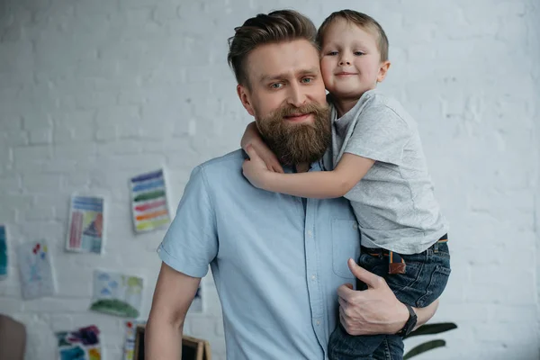 Porträtt Leende Far Håller Lille Son Och Tittar Kameran Hemma — Stockfoto