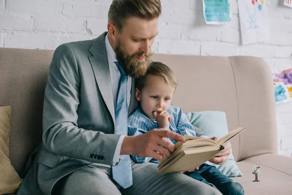 Businessman Little Son Reading Book Together Sofa Home Work Life — Stock Photo, Image