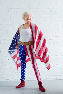 proud senior sportswoman posing with american flag and smiling at camera clipart