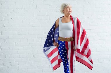 serious senior sportswoman holding us flag and looking away clipart