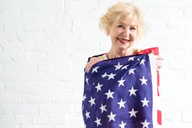 Amerikan bayrağı tutarak ve kameraya gülümseyen güzel kadın kıdemli
