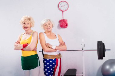 çapraz kolları ile ayakta ve spor salonunda kamera gülümseyen kıdemli sportswomen 